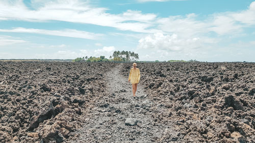 Rear view of man standing on land against sky