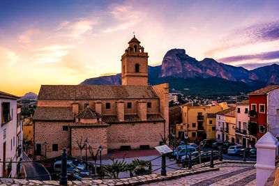 Buildings in city against sky at sunset