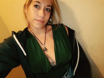 Portrait of young woman standing against wall at home