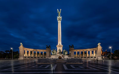 Statue in city against sky at night