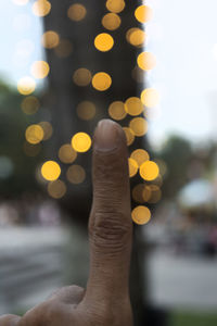 Close-up of cropped finger against defocused lights