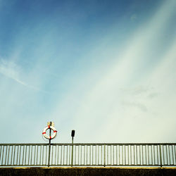 Low angle view of life belt on bridge railing against sky