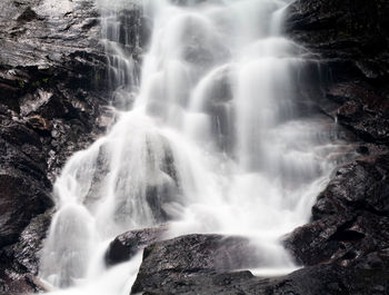 Low angle view of waterfall along rocks