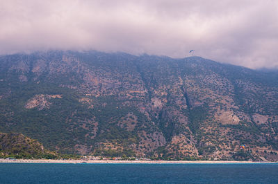 Scenic view of sea and mountains against cloudy sky