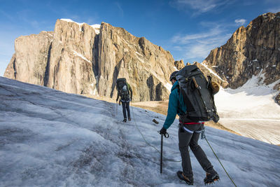 People walking on snow covered mountain against sky