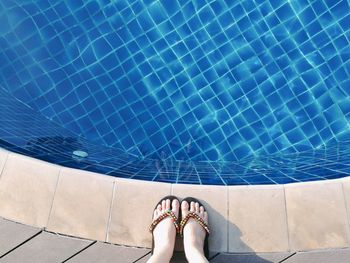 Low section of woman standing by swimming pool