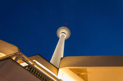Low angle view of illuminated building and fernsehturm against clear blue sky