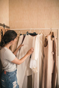 Female customer browsing through dresses on rack at workshop