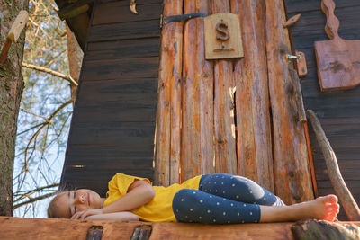 Low section of woman sitting on wooden wall