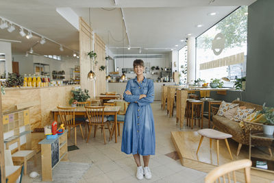 Smiling female entrepreneur with arms crossed standing in coffee shop