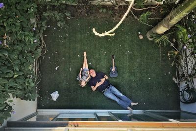 Directly above shot of grandfather relaxing with granddaughter at yard