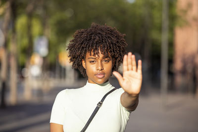 Young woman making a stop or stop gesture with the raised palm of her hand as she blocks access 