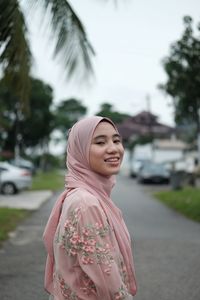 Smiling young woman looking away while standing on road