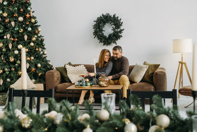 Rear view of woman sitting by christmas tree