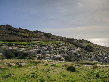 Scenic view of rocks by sea against sky