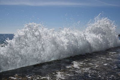 Water splashing in sea against sky