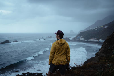 Rear view of man looking at sea against sky