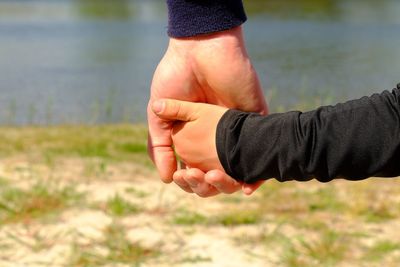 Father's large hand hold hand of a boy. hands in blue and black shirts.