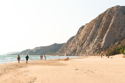 People on beach against clear sky