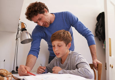 Father assisting boy while doing homework