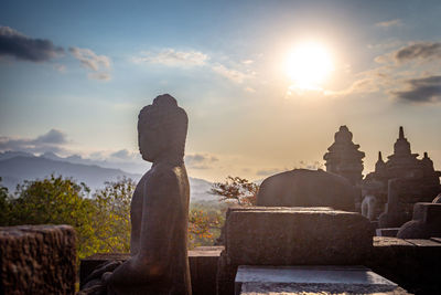 Statue in temple against sky during sunset