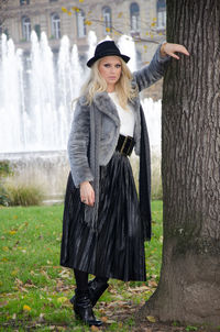 Young man standing by tree trunk