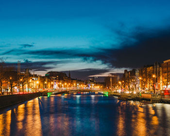 Illuminated buildings by river at night