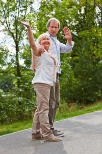 Full length of of senior couple standing on road against trees