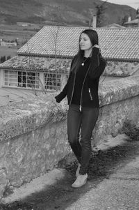 Full length portrait of young woman standing on bridge