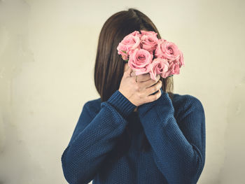 Close-up of woman standing by pink roses