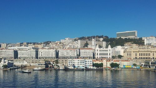 Buildings in city against clear blue sky