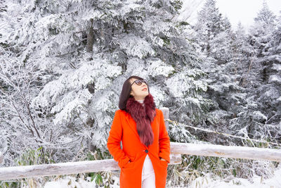 Young woman standing against snow covered trees during winter