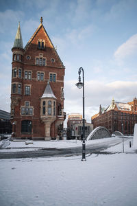 Houses by street against sky in city during winter