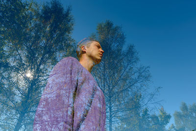 Low angle view of man looking at tree against sky