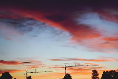 Low angle view of silhouette electricity pylon against dramatic sky