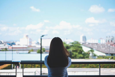 Rear view of woman on railing against sky