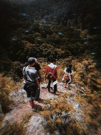 Rear view of people walking on rocks in forest