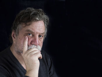 Close-up of thoughtful mature man against black background