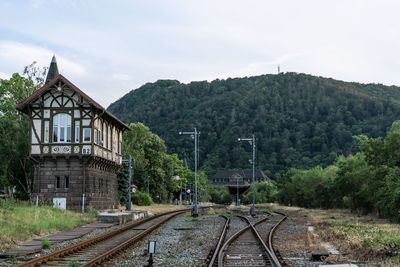 Railroad tracks amidst trees and mountains against sky