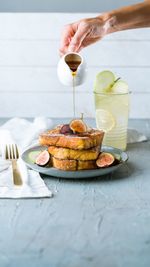 Cropped hand of person pouring honey on baked bread over table