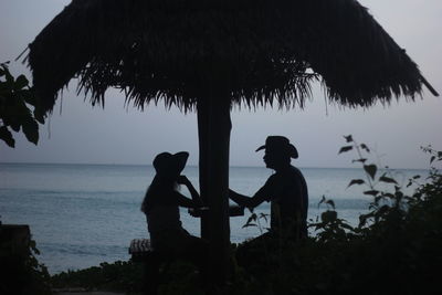 Silhouette people by sea against sky