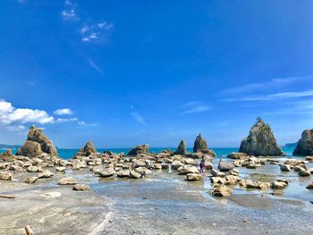 Rocks on beach against blue sky