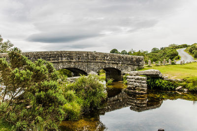 Arch bridge over river against sky