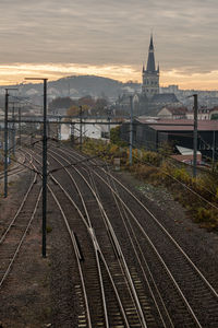 Railroad tracks amidst buildings against sky during sunset