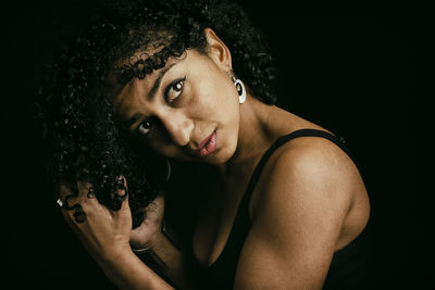 Portrait of young woman against black background