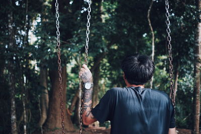 Rear view of man sitting on swing