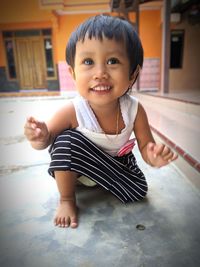 Full length of cute girl kneeling on floor at home