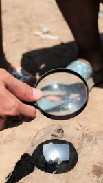 Cropped hand holding magnifying glass over paper