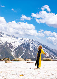 Rear view of woman standing on snowcapped mountain