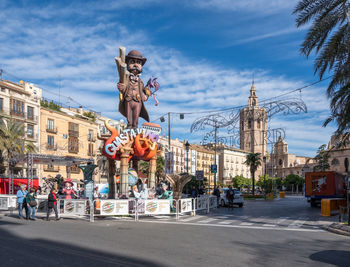 Statue by road against buildings in city against sky